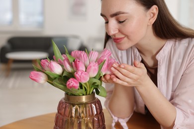 Photo of Beautiful woman with bouquet of pink tulips at home