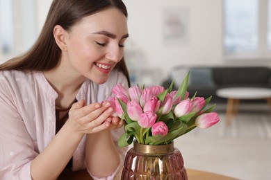 Photo of Smiling woman with bouquet of pink tulips at home