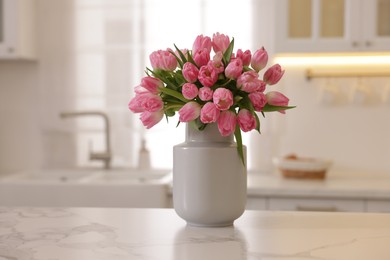 Photo of Bouquet of beautiful tulips in vase on white marble counter in kitchen