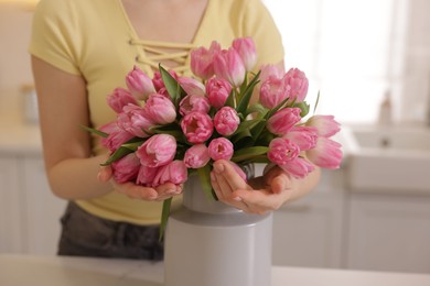 Photo of Woman with bouquet of pink tulips at table indoors, closeup