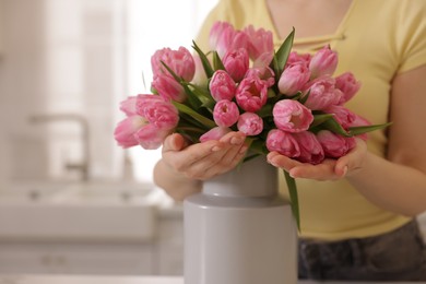 Photo of Woman with bouquet of pink tulips indoors, closeup. Space for text