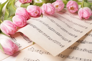 Photo of Beautiful tulips on sheets with music notes, closeup