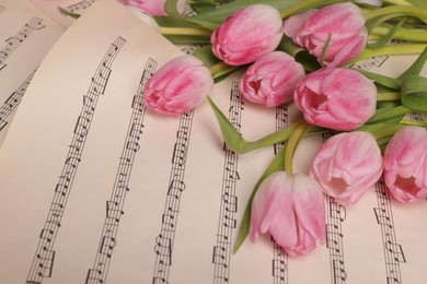 Photo of Beautiful tulips on sheets with music notes, above view