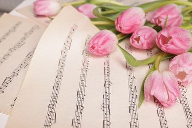 Photo of Beautiful tulips on sheets with music notes, closeup