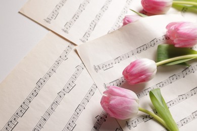 Photo of Beautiful tulips and sheets with music notes on white table, above view