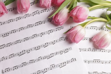 Photo of Beautiful tulips on sheets with music notes, top view