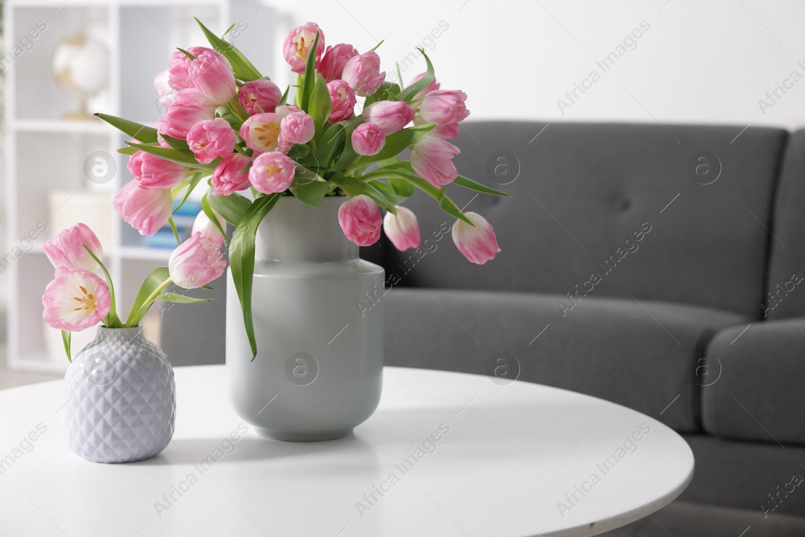 Photo of Beautiful tulips in vases on table indoors. Space for text