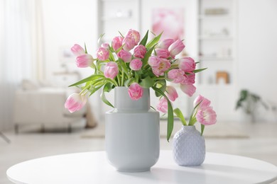 Photo of Beautiful tulips in vases on table indoors