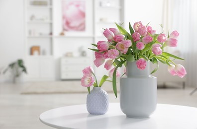 Photo of Beautiful tulips in vases on table indoors. Space for text