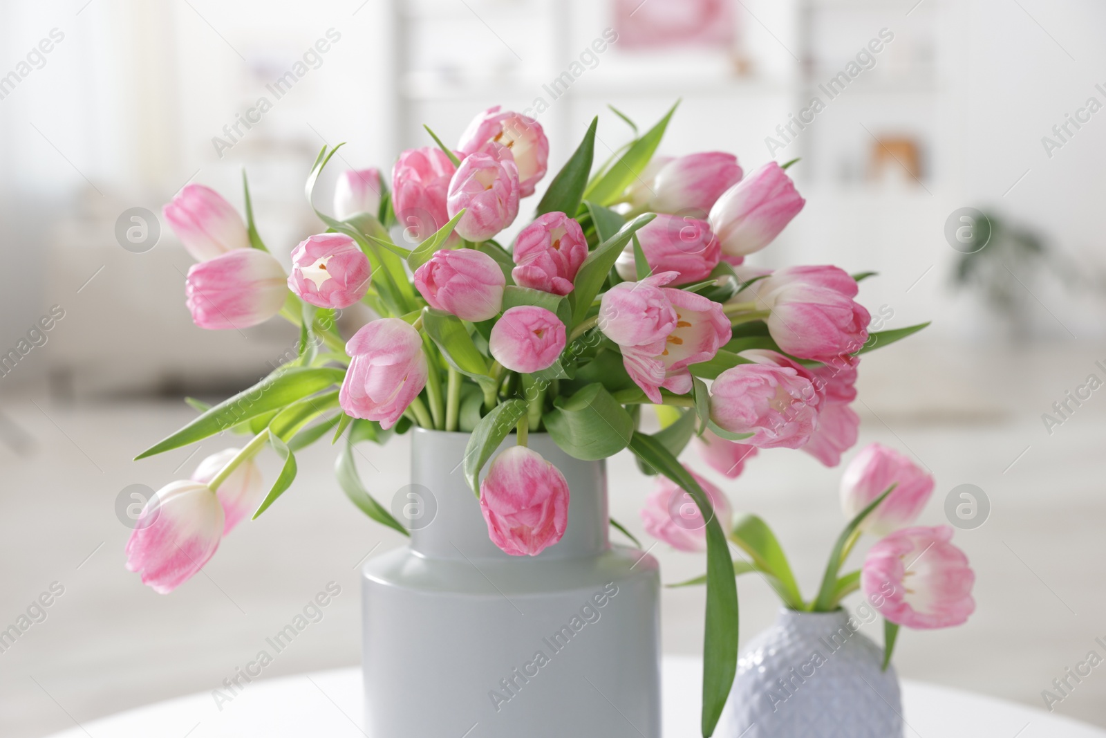 Photo of Beautiful tulips in vases on table indoors