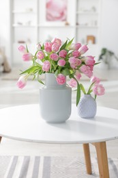 Photo of Beautiful tulips in vases on coffee table indoors