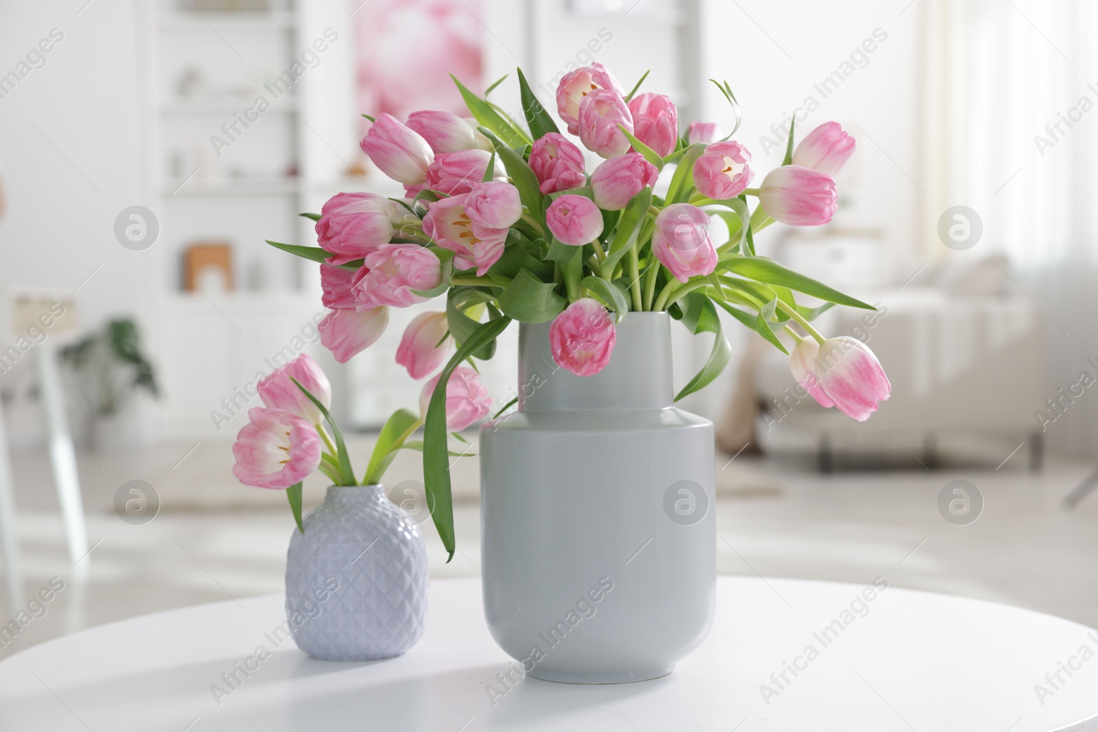 Photo of Beautiful tulips in vases on table indoors