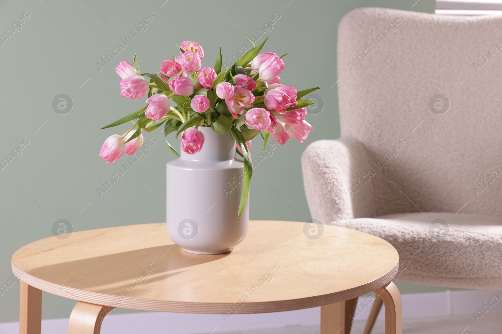 Photo of Bouquet of beautiful tulips in vase on table indoors