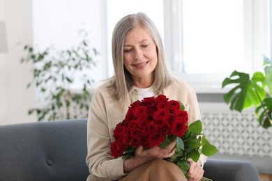 Photo of Smiling woman with bouquet of roses on sofa at home