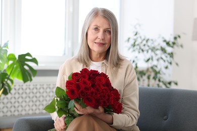 Photo of Beautiful woman with bouquet of roses on sofa at home