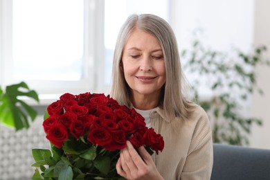 Photo of Smiling woman with bouquet of roses at home