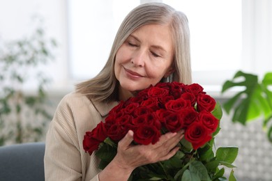 Photo of Beautiful woman with bouquet of roses at home