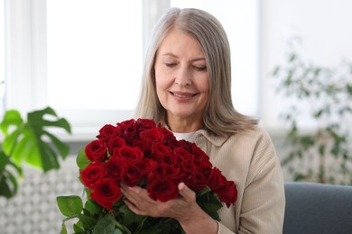 Photo of Smiling woman with bouquet of roses at home