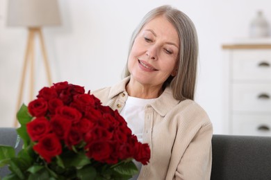 Photo of Smiling woman with bouquet of roses on sofa at home