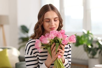 Photo of Beautiful woman with bouquet of tulips at home