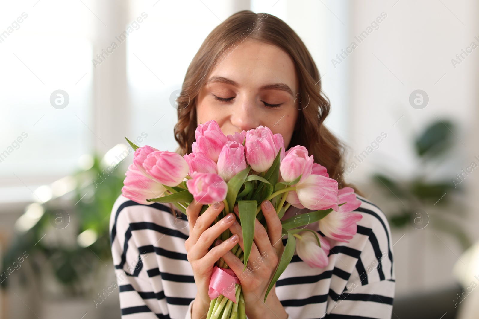 Photo of Beautiful woman with bouquet of tulips at home