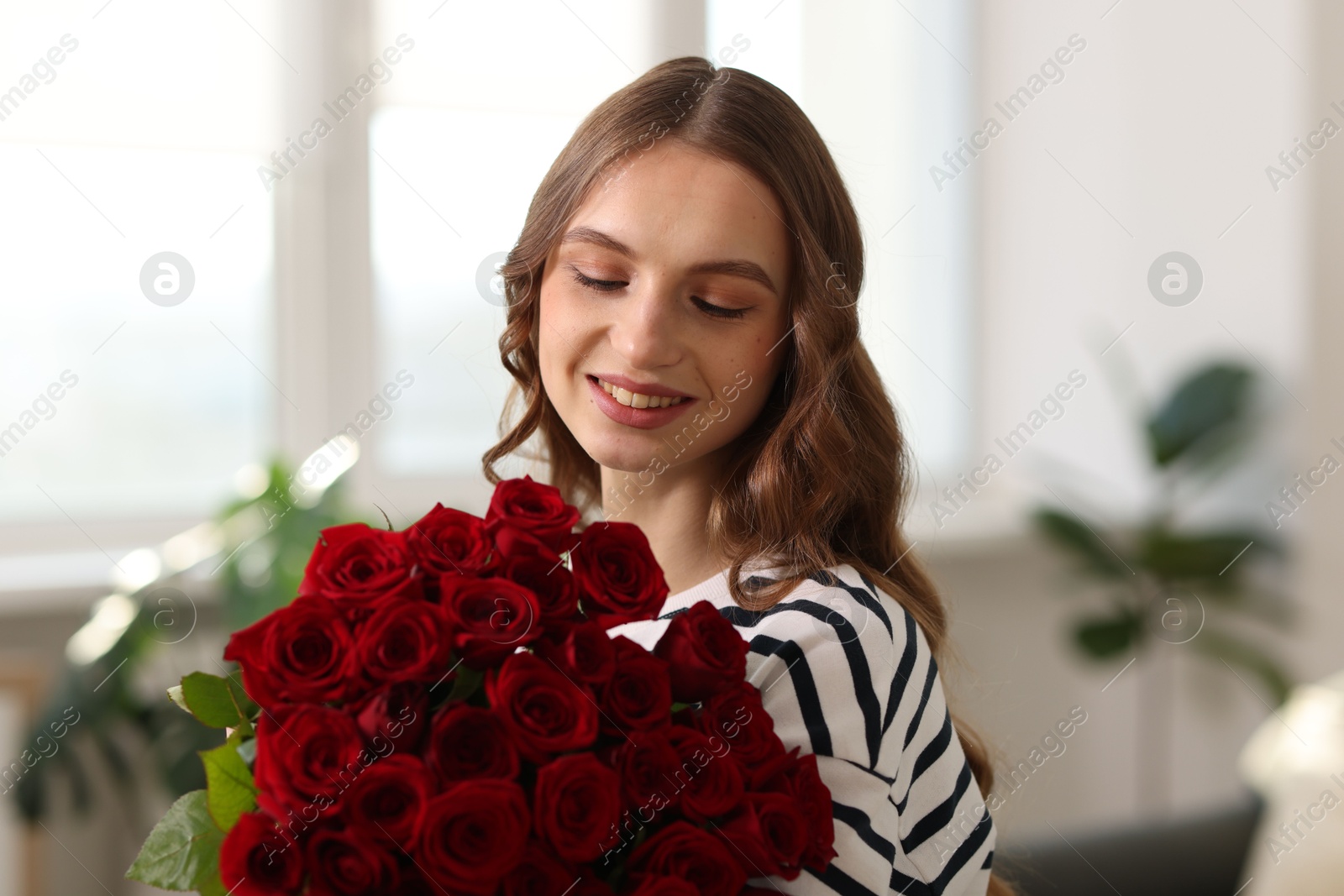 Photo of Smiling woman with bouquet of roses at home