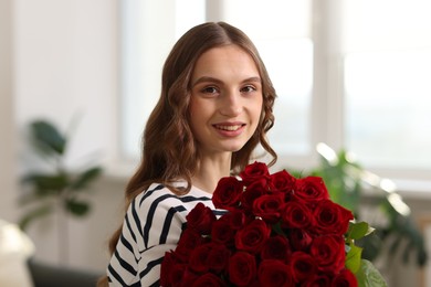 Photo of Smiling woman with bouquet of roses at home