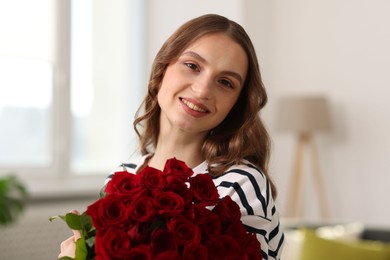 Photo of Smiling woman with bouquet of roses at home