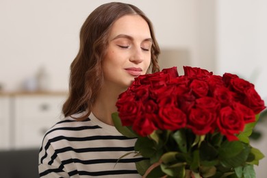 Photo of Beautiful woman with bouquet of roses at home