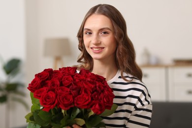 Photo of Smiling woman with bouquet of roses at home