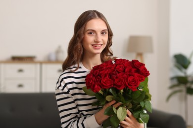 Photo of Smiling woman with bouquet of roses at home