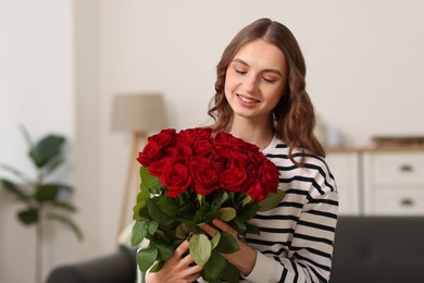 Photo of Smiling woman with bouquet of roses at home