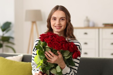 Photo of Smiling woman with bouquet of roses at home