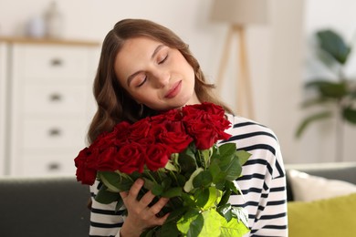 Photo of Beautiful woman with bouquet of roses at home