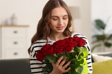 Photo of Smiling woman with bouquet of roses at home