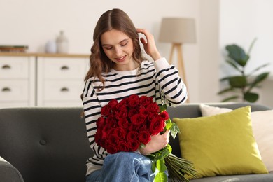 Photo of Smiling woman with bouquet of roses on sofa at home