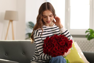 Photo of Smiling woman with bouquet of roses on sofa at home