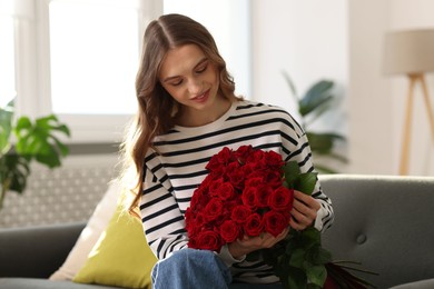 Photo of Smiling woman with bouquet of roses on sofa at home