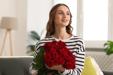 Photo of Smiling woman with bouquet of roses at home