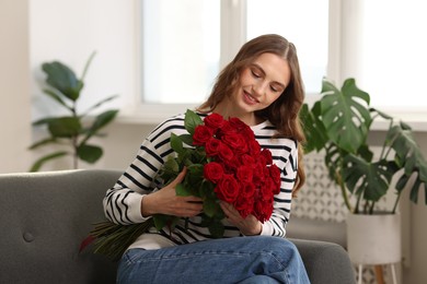 Photo of Smiling woman with bouquet of roses on sofa at home