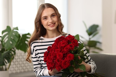 Photo of Smiling woman with bouquet of roses at home