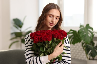 Photo of Beautiful woman with bouquet of roses at home