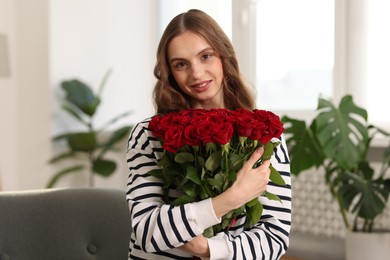 Photo of Smiling woman with bouquet of roses at home