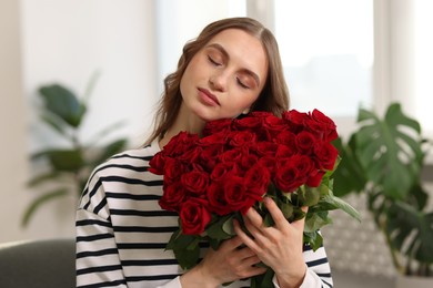 Photo of Beautiful woman with bouquet of roses at home