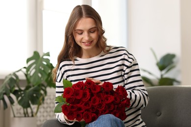 Photo of Smiling woman with bouquet of roses on sofa at home