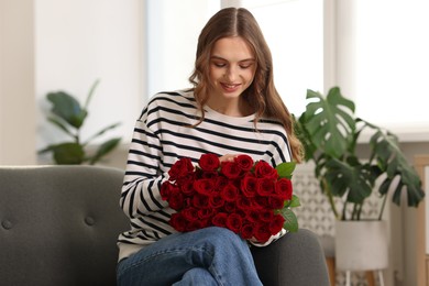 Photo of Smiling woman with bouquet of roses on sofa at home