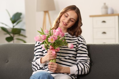 Photo of Smiling woman with bouquet of tulips on sofa at home