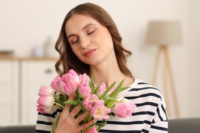 Photo of Beautiful woman with bouquet of tulips at home