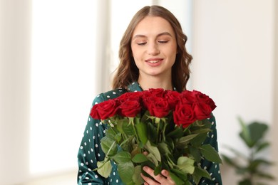 Photo of Smiling woman with bouquet of roses at home