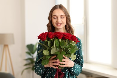 Photo of Smiling woman with bouquet of roses at home